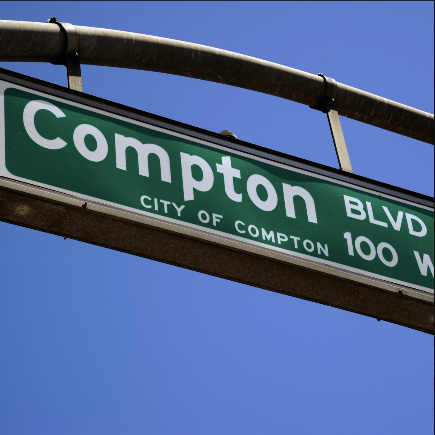 Compton Blvd street sign against blue sky showing City of Compton 100 W